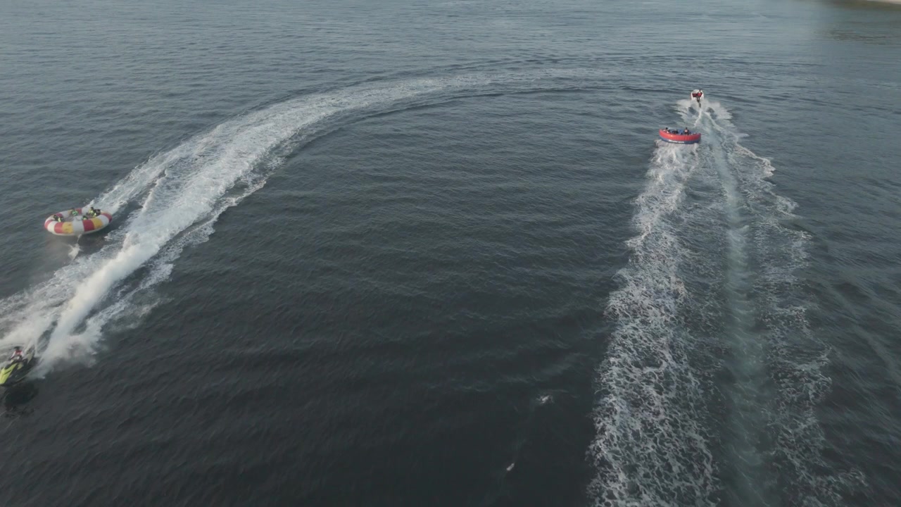 Vista drone di persone su ciambella gonfiabile e moto d'acqua in mare aperto.