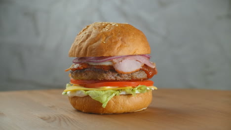 Yummy-fast-food-concept.-Fresh-homemade-grilled-burger-with-meat-patty-tomatoes-cucumber-lettuce-onion-and-sesame-seeds.-Unhealthy-lifestyle.-Food-background.