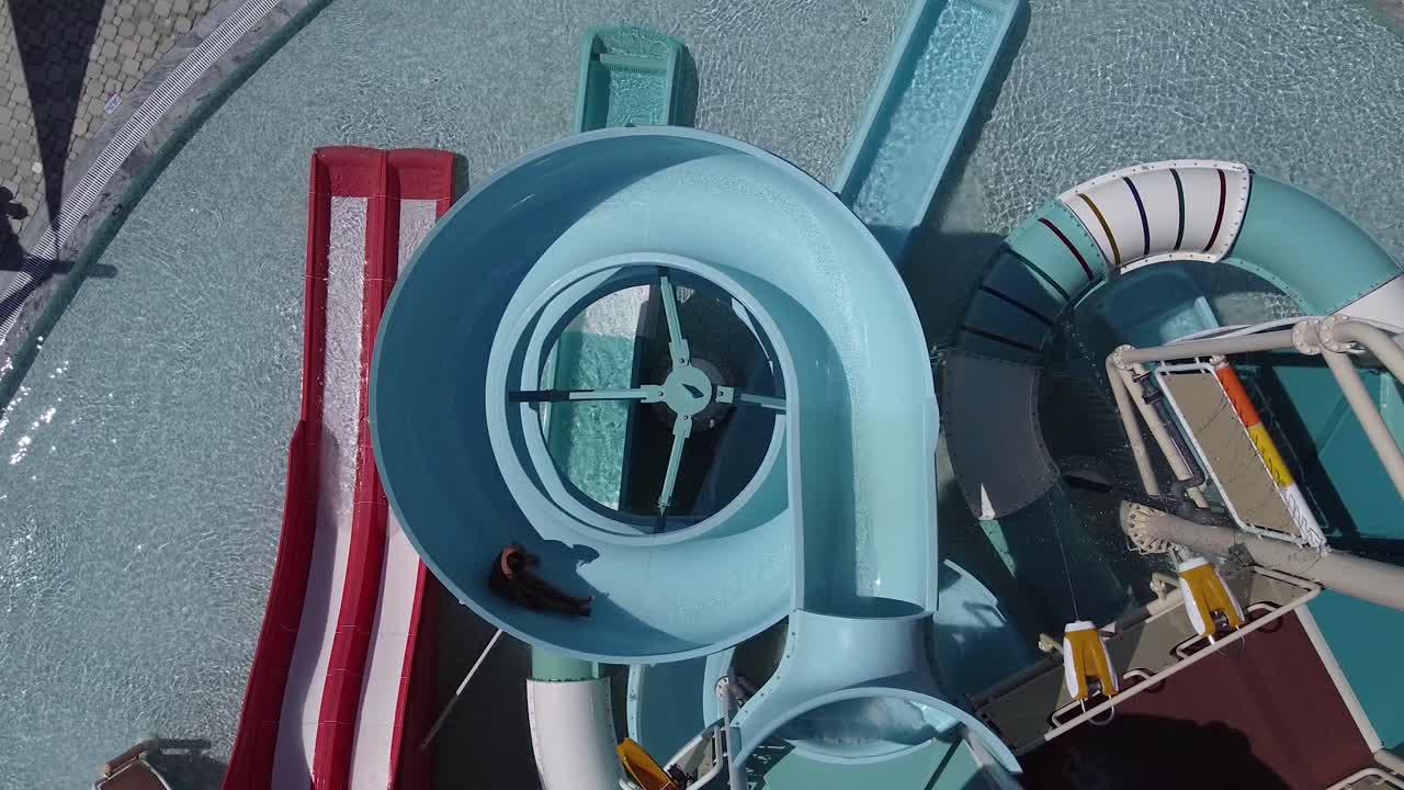 一位小女孩在空的水上公园里骑着螺旋滑水道