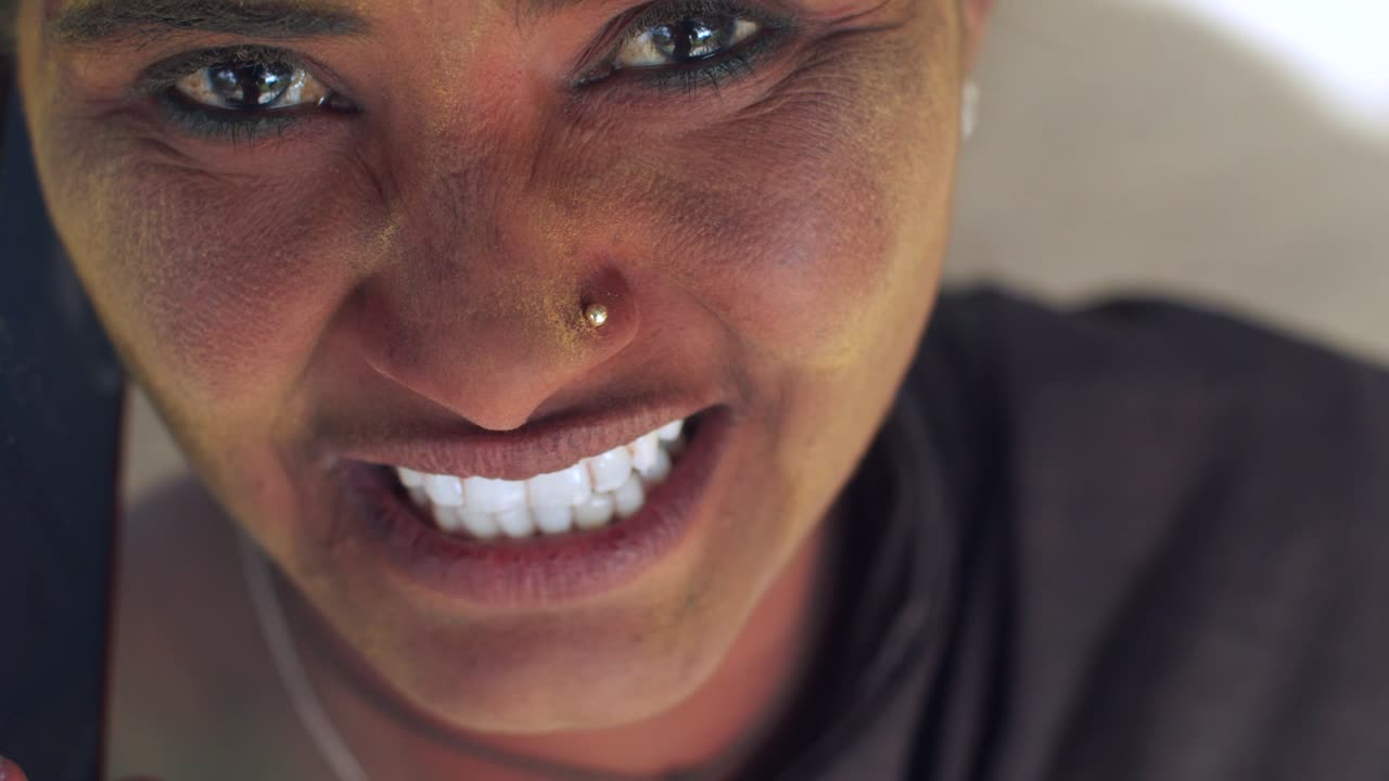 인도 여성의 가까운 얼굴은 밝은 홀리 색으로 얼룩져 있습니다.