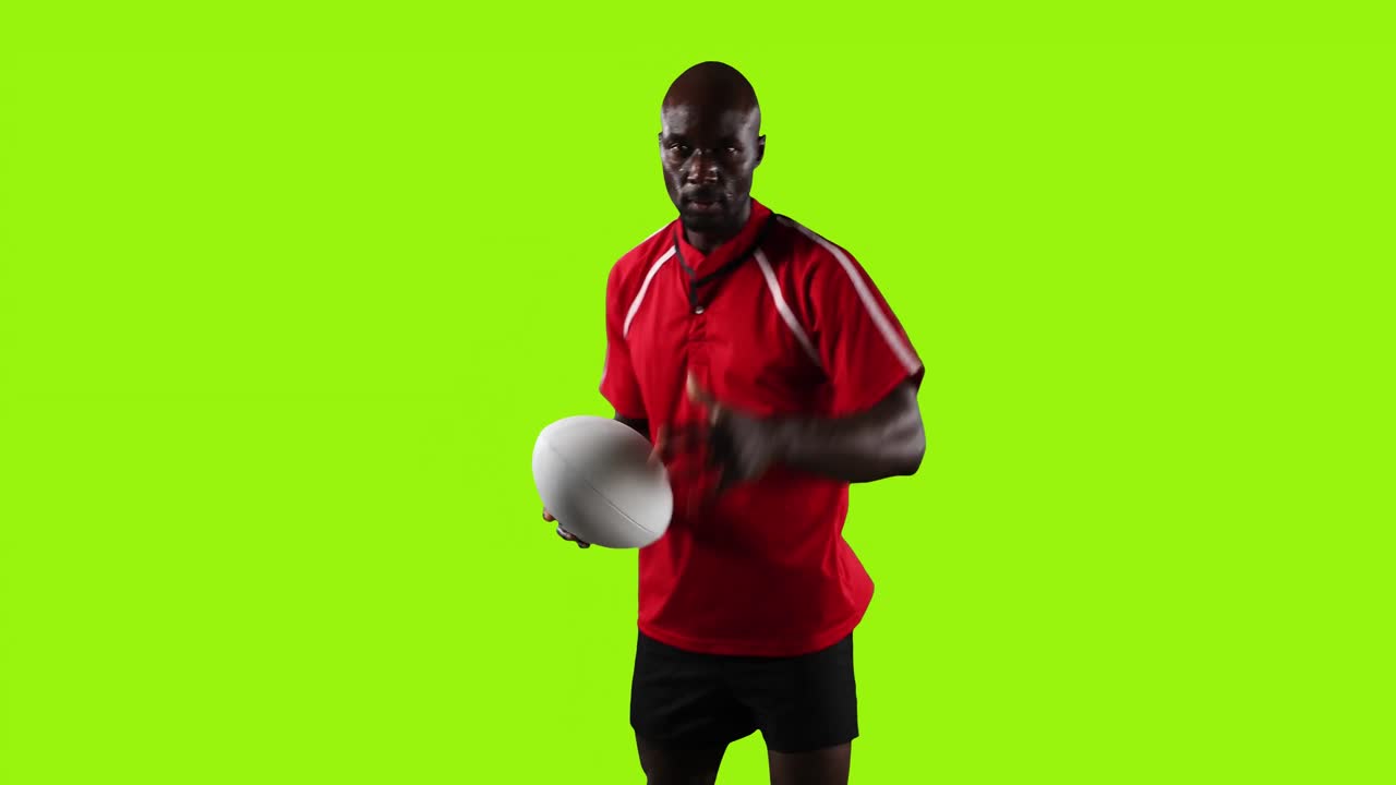 Professional rugby player standing and pointing with a ball on green background 4k