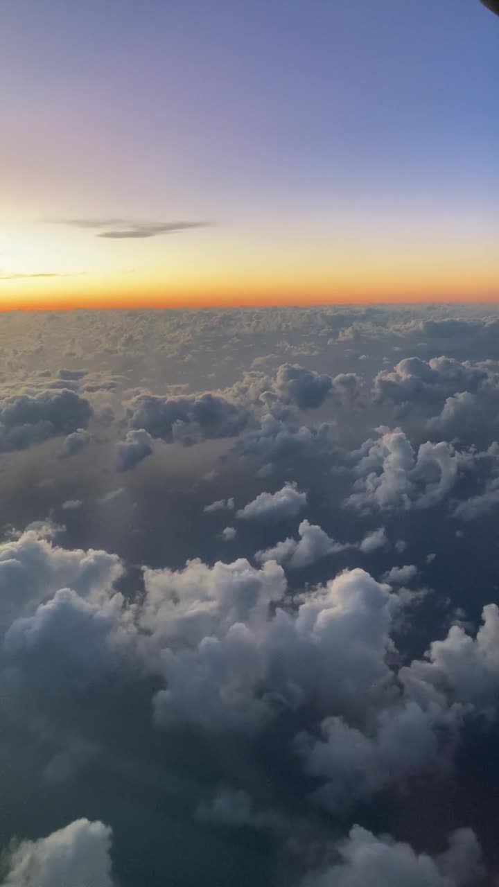 Vertikal telefonoptagelse af skyer ovenfra, set fra et fly ved solnedgang