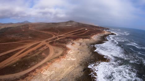 Coastline-from-above,-static,-multiple-dirt-roads,-crashing-ocean-waves,-4k-60fps