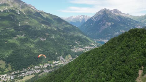 paraglider floating above eau d'olle valley in alpe d' huez, french alps - pan left