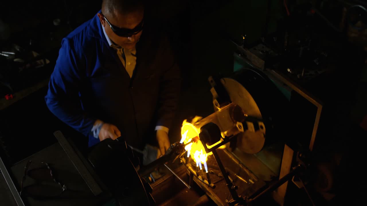 vista de alto ángulo de un trabajador masculino soplando vidrio en una fábrica de vidrio 4k