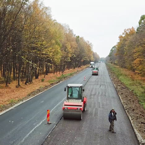 heavy equipment while building an asphalt road. steamroller pressing new asphalt in highway in autumn. road works on natural background.