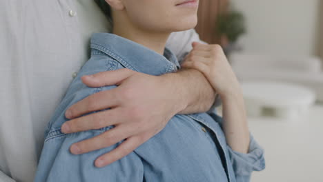 close up of a handsome man tenderly hugging his girlfriend from the back at home