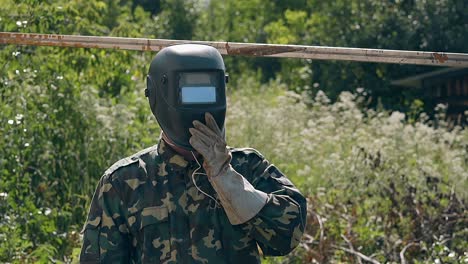 slow motion handyman takes off welding mask in yard