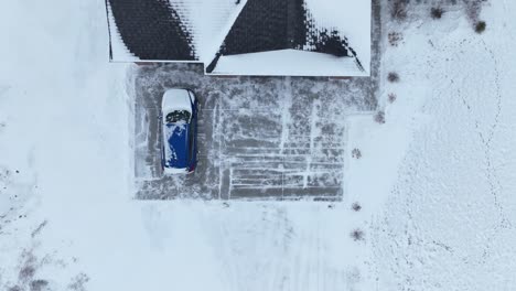 una toma aérea de un avión no tripulado de un coche azul en una calzada cubierta de nieve