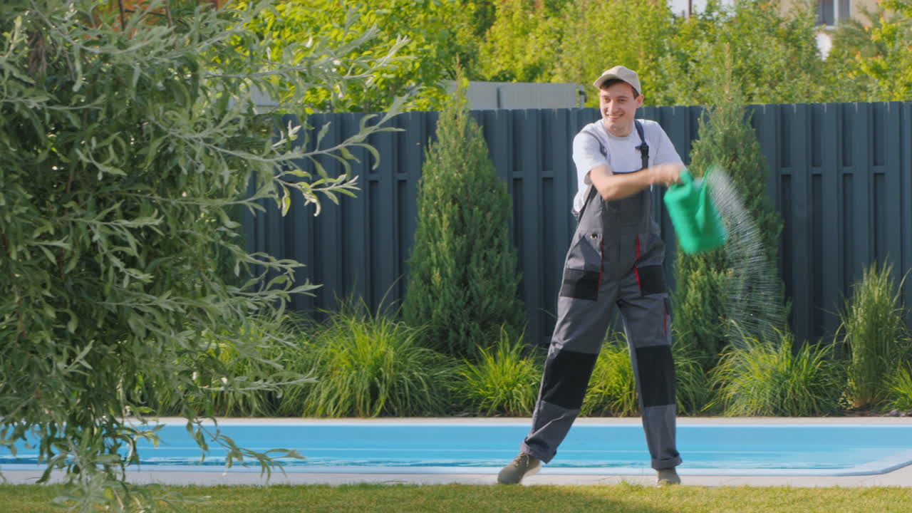 jardinero regando plantas cerca de una piscina