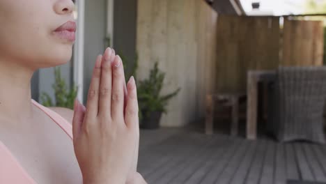 mujer biracial enfocada practicando yoga y meditando en el jardín en cámara lenta