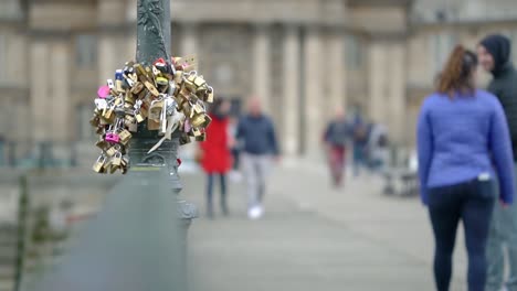 clip of love locks on a pole in paris city centre with people walking out of focus blur in the background