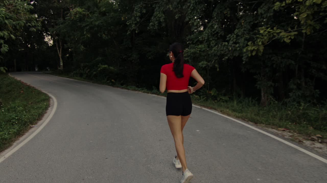 Woman Running on Winding Road Through Forest