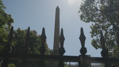 Obelisk-landmark-behind-steel-sharp-fence,-motion-view-along-fence