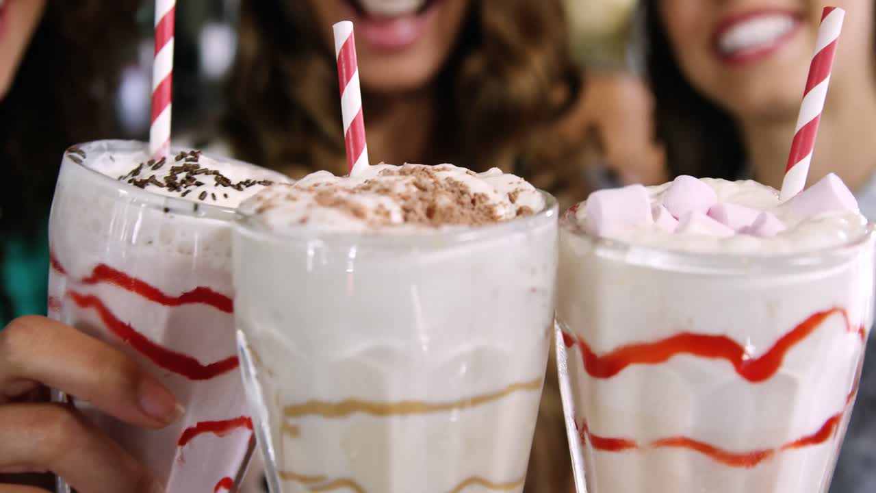Gülümseyen kadın arkadaşlar smoothie kadehleriyle kadeh tokuşturuyor