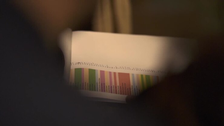 Mano che tiene un elenco di libri per la pianificazione di eventi con codifica a colori, dettagliato e organizzato.