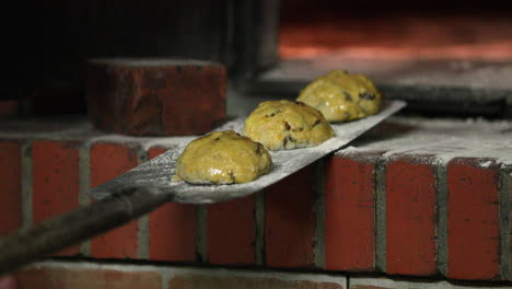 baker put the cookie dough with raisins inside the oven by metal peel (shovel-like). - close up shot