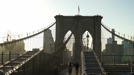 commuters crossing brooklyn bridge in new york on a sunny evening