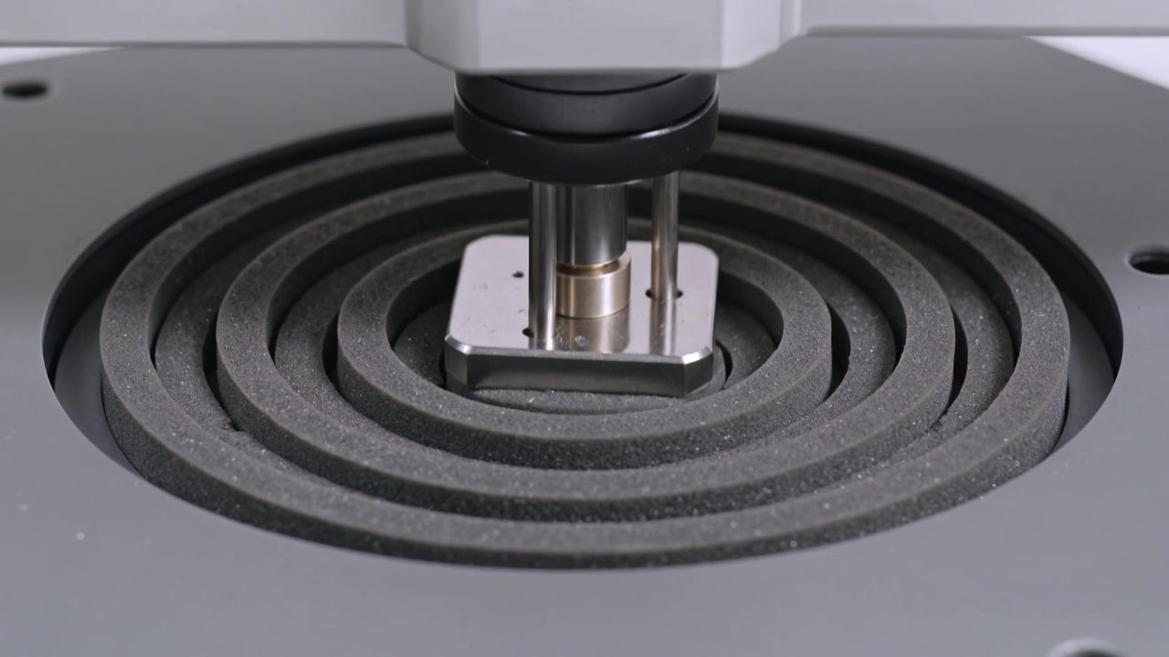Actuating probe and mount plate lowering into foam rings on platform, compressing for test
