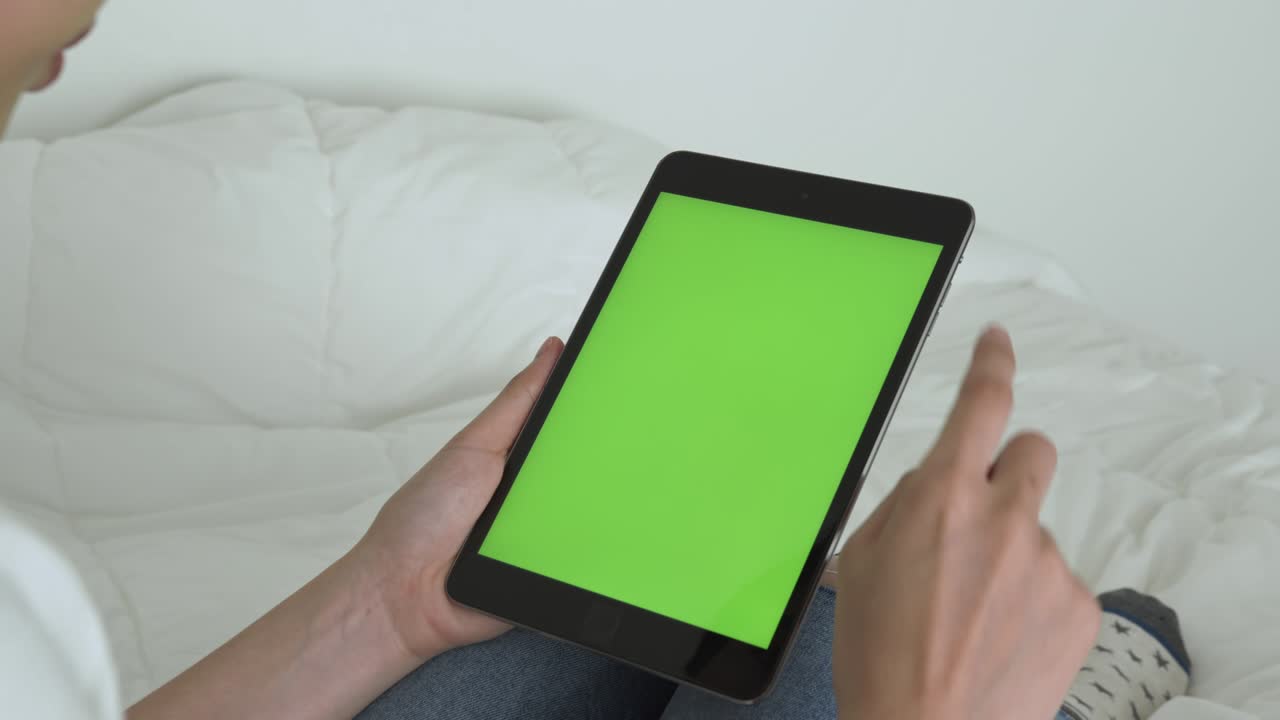 mujer sosteniendo una tableta digital con pantalla verde y dispositivo táctil navegando por internet.