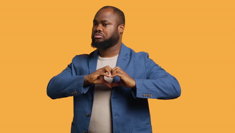 portrait of jolly man doing heart symbol shape, studio background