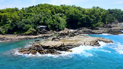 People-stand-on-cliffs-by-wavy-blue-water-at-tourist-spot-in-Indonesia