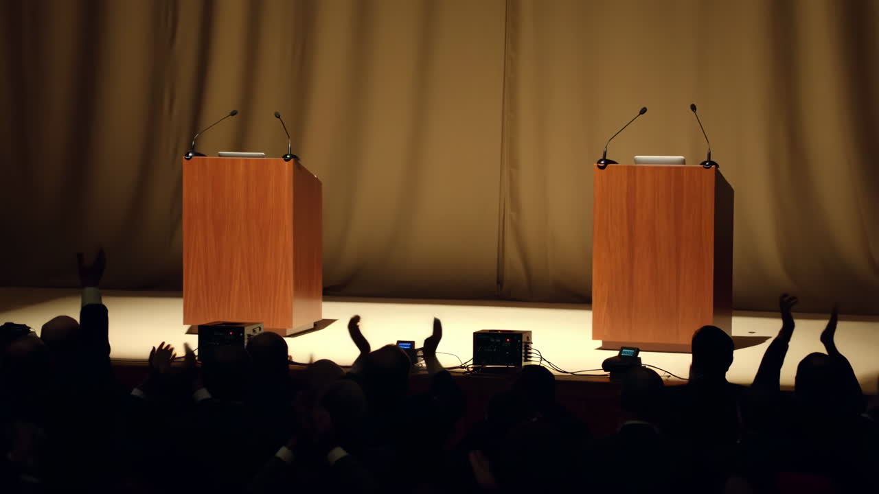Two podiums on a stage with an audience