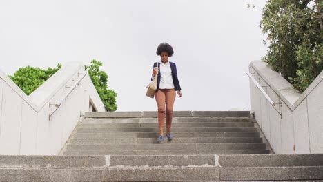 mujer de negocios afroamericana con café para llevar y caminando
