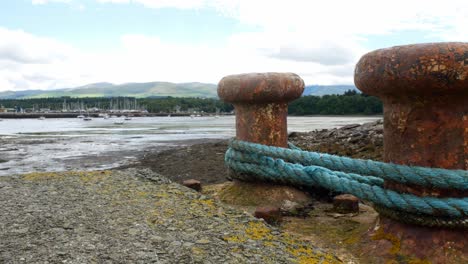 rusty metal mooring with rope overlooking coastal fishing harbour dolly left