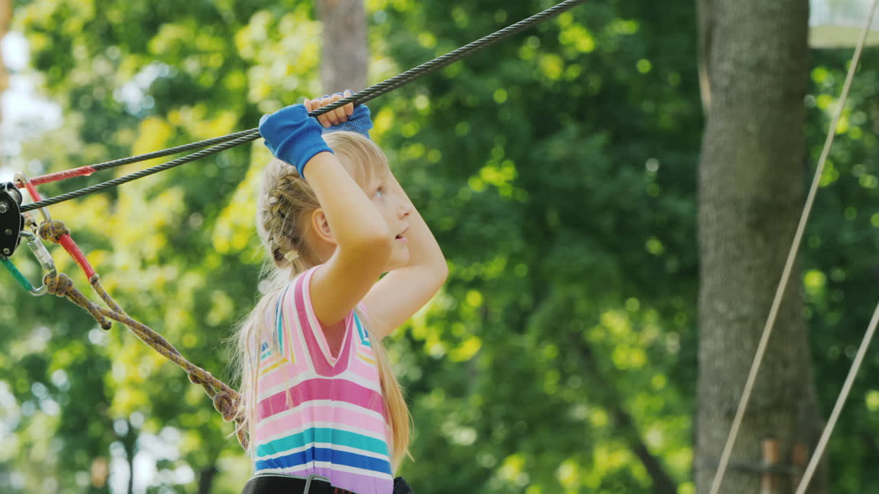 una chica valiente se mueve a lo largo de las cuerdas entre los árboles usa una cuerda de seguridad