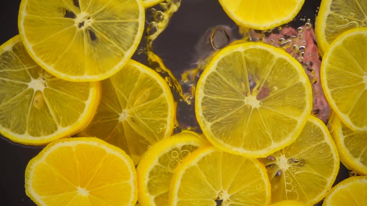 Rodelas de limão fresco enquanto se prepara limonada numa travessa de vidro. Vista inferior.