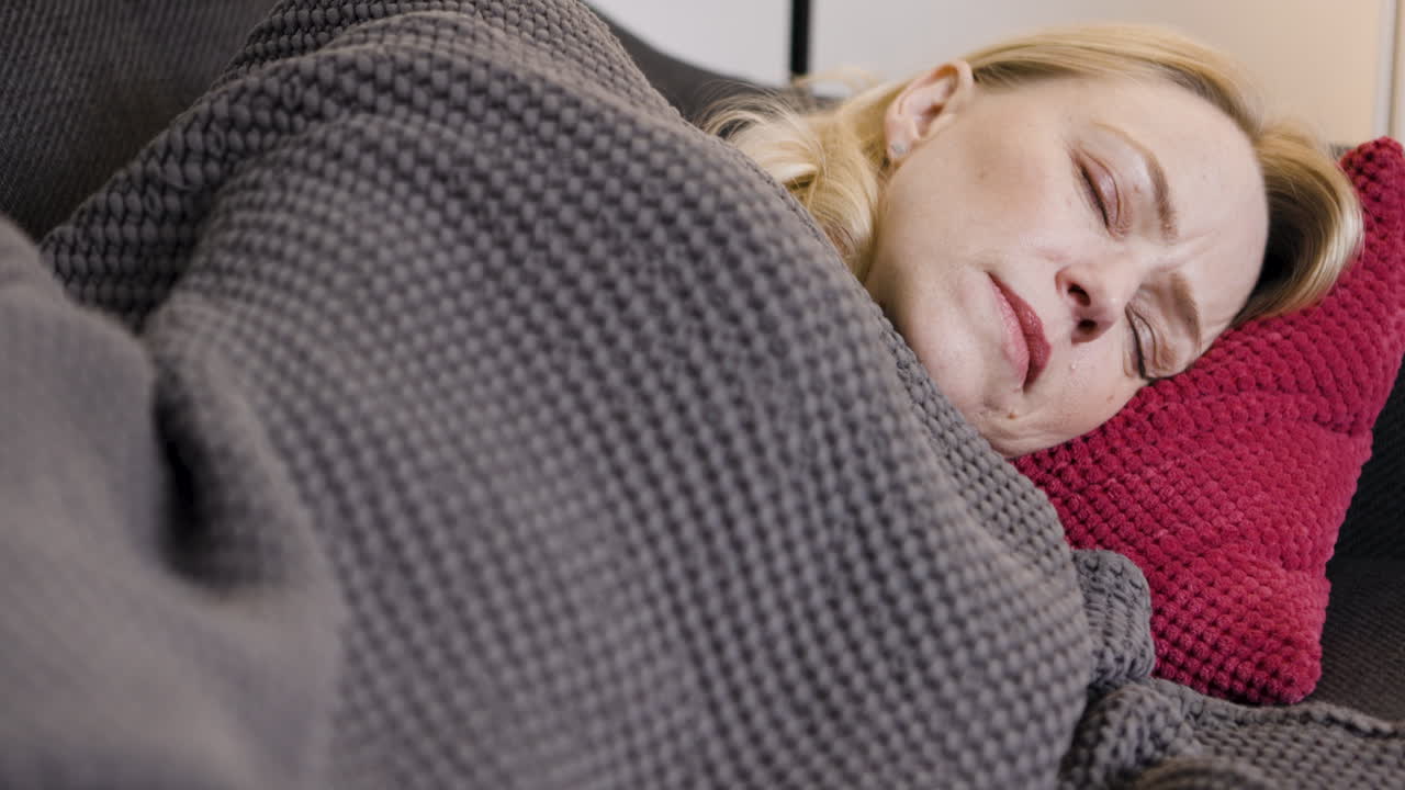 Woman sleeping on a couch with a blanket and pillow