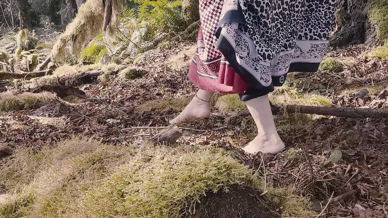 Woman shaman walking right to left through lush moss covered rainforest honoring her ancestors for her abundance