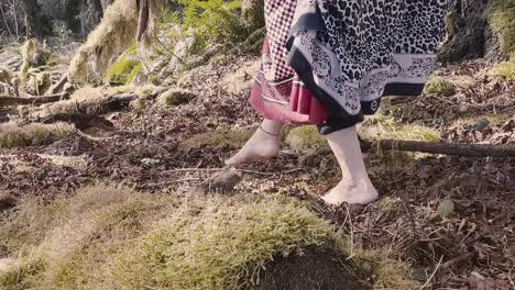 woman shaman walking right to left through lush moss covered rainforest honoring her ancestors for her abundance
