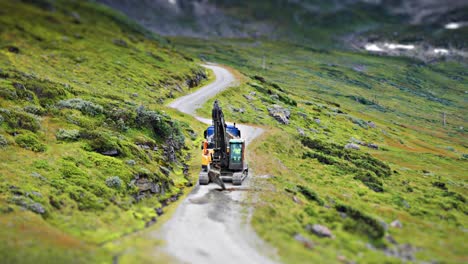 a tilt-shift video of the excavator and a lorry on the unpaved road conducting road maintenance