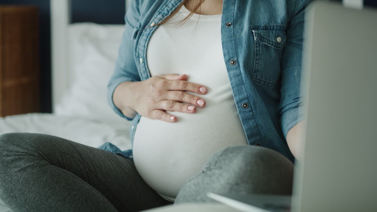 노트북을 사용하는 임산부의 비디오를 아래로 기울입니다.