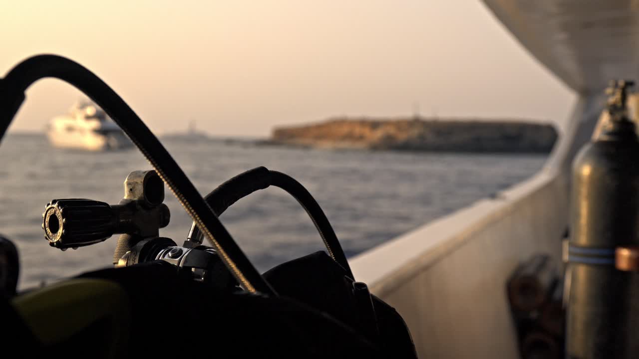 Little Brother Island al tramonto. Le scogliere rocciose e aride dell'isola sono illuminate dalla luce calda e tenue, proiettando tonalità dorate sulla pietra e sulle acque scure e agitate del Mar Rosso.
