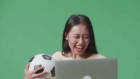 mujer emocionada viendo un juego de fútbol en una computadora portátil