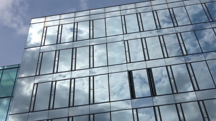 Time-lapse di un cielo estivo blu con nuvole che si riflettono sulla facciata in vetro di un edificio per uffici
