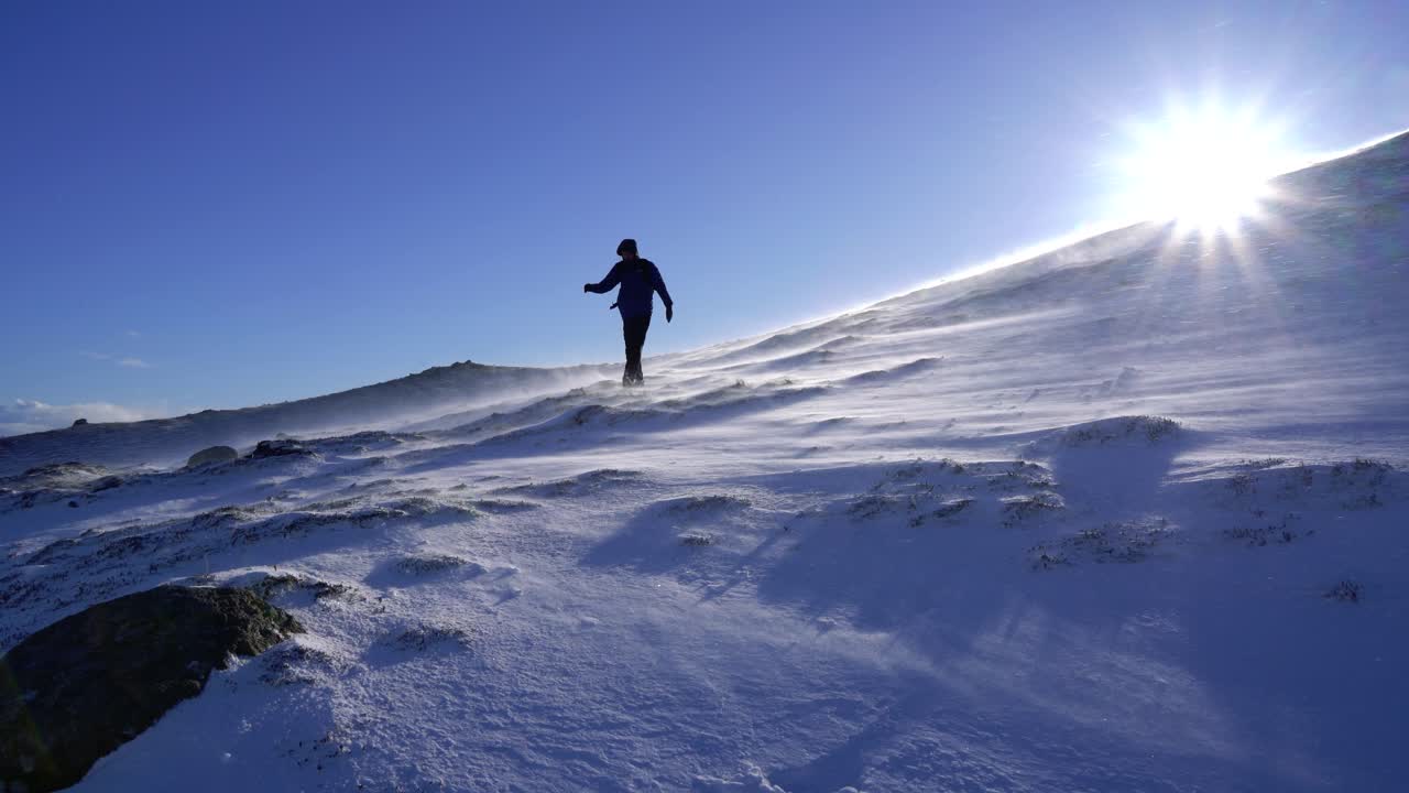 caminante caminando entre la nieve que sopla en la ladera de una montaña en invierno en scotlad