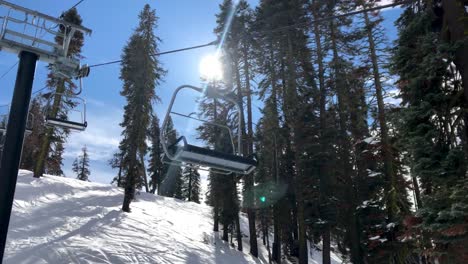 ski lift in winter moving over snow covered mountain with sun shining through pine trees