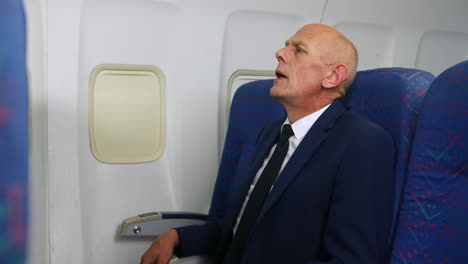 un hombre de negocios maduro sintiendo presión de la cabina en sus oídos en un avión de pasajeros