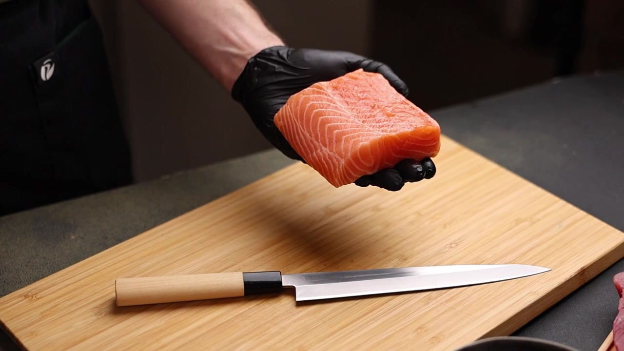 Chef's Hand in Black Glove Holding Fresh Salmon Fillet