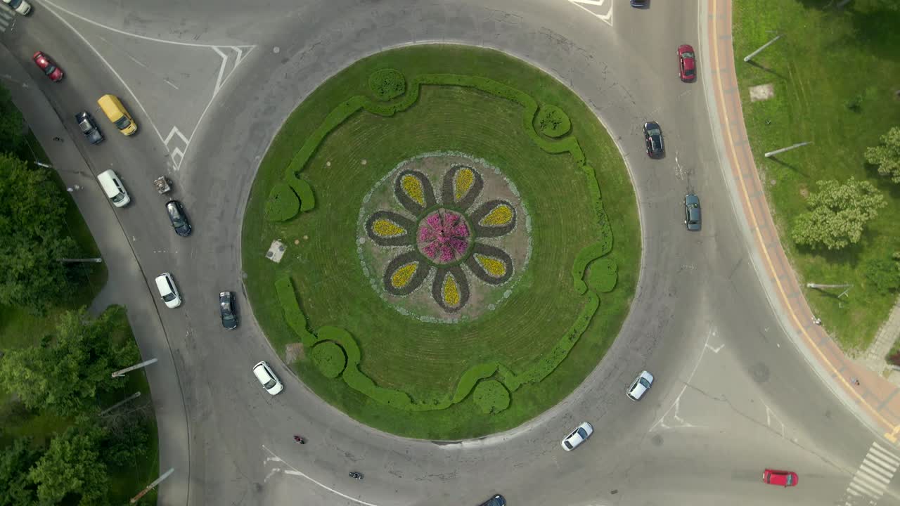 4k slow motion aerial view of roundabout road with circular cars in small european city at sunny day