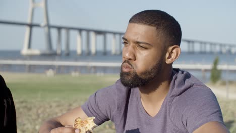 smiling handsome african american man eating pizza.