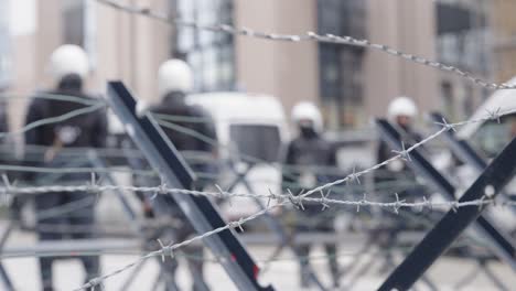 unrecognizable riot police in full riot gear backed by anti-riot vans cordon off a street during a demonstration - defocused shot