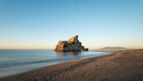 sunrise at a rock in the sea on malaga beach in spain