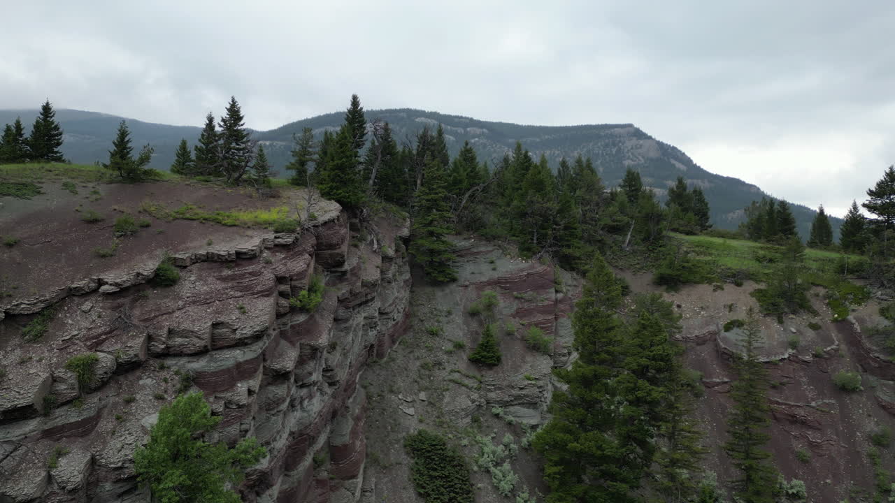 acantilado a la orilla del río a la claridad del bosque con granero y montañas en la distancia - día exterior nublado - imágenes aéreas de 4k