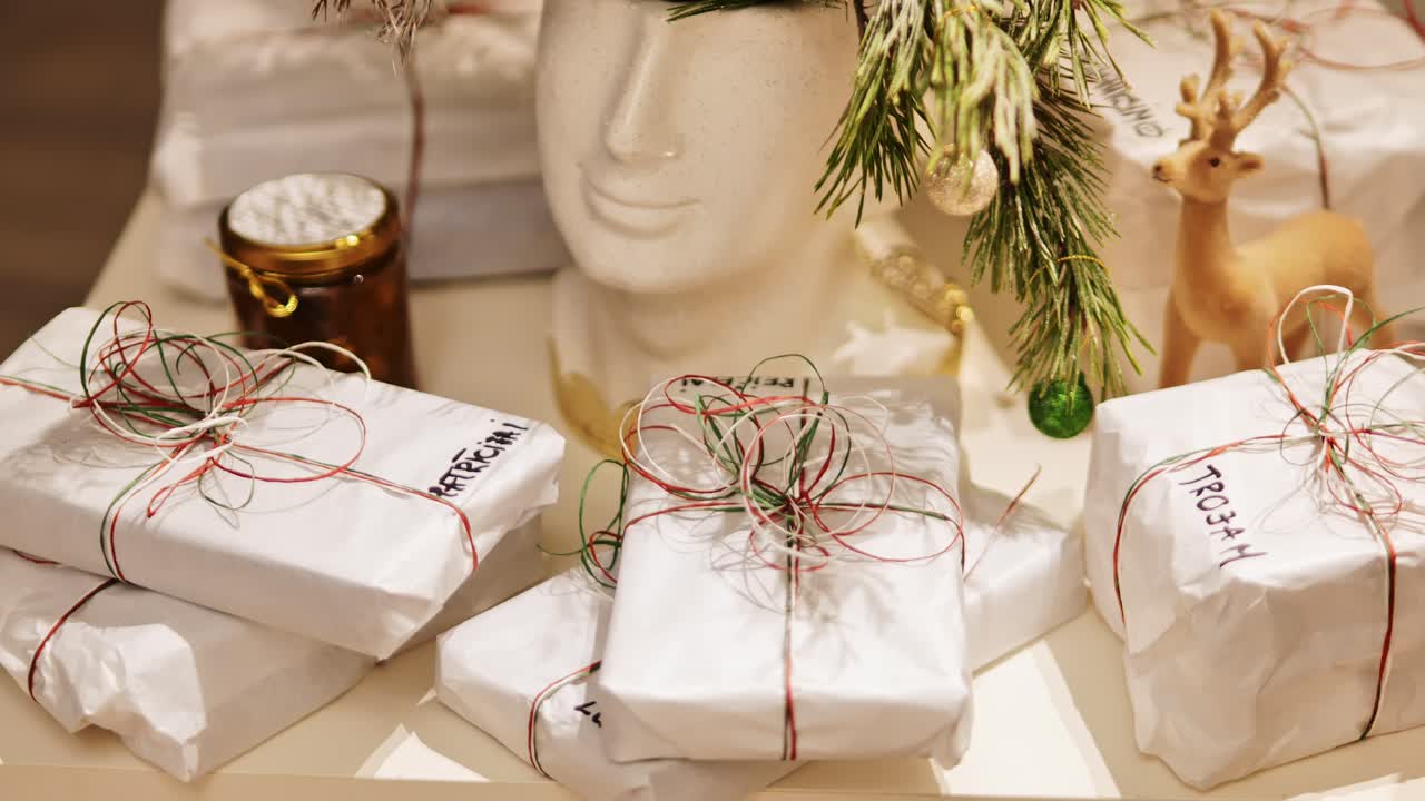 Holiday decor featuring wrapped Christmas gifts, greenery, and reindeer ornament