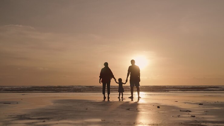 夕暮れの家族がビーチで散歩する